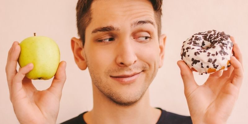 A young man refusing a cake offered by his mother, symbolizing food control and the emotional connection to food, illustrating why we struggle with food