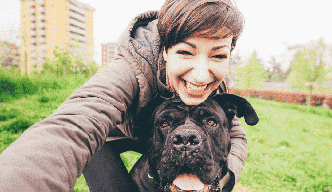 An authentic woman with natural wrinkles and gray hair smiling peacefully with her dog