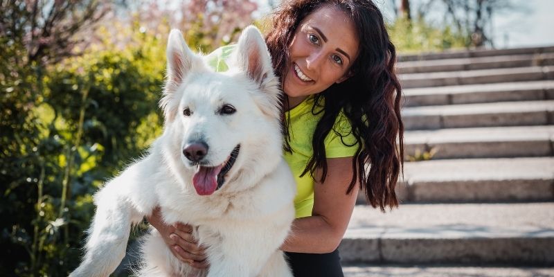 A young woman interacting with her white dog showing how the owner's inner state shapes the dog's health