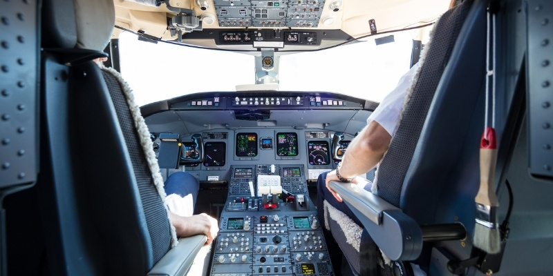 View from inside an airplane cockpit with pilots operating complex flight controls illustrating the airplane metaphor for aggression in dogs