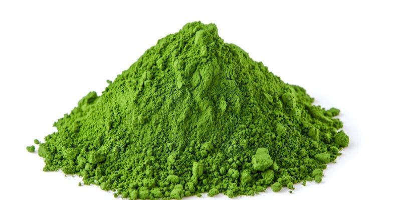 Pile of fine green herbal detox powder on a white background supporting why dogs eat grass treatment