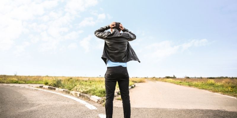 Man standing at a crossroads holding his head representing truth creates resistance and choice